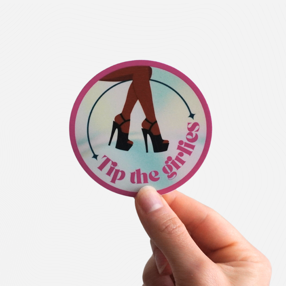 Circular sticker with 'Tip the girlies' text held by a hand on a white background