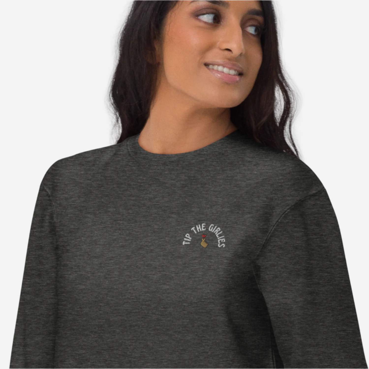 Woman in front of a white background wearing a dark grey sweater with the words 