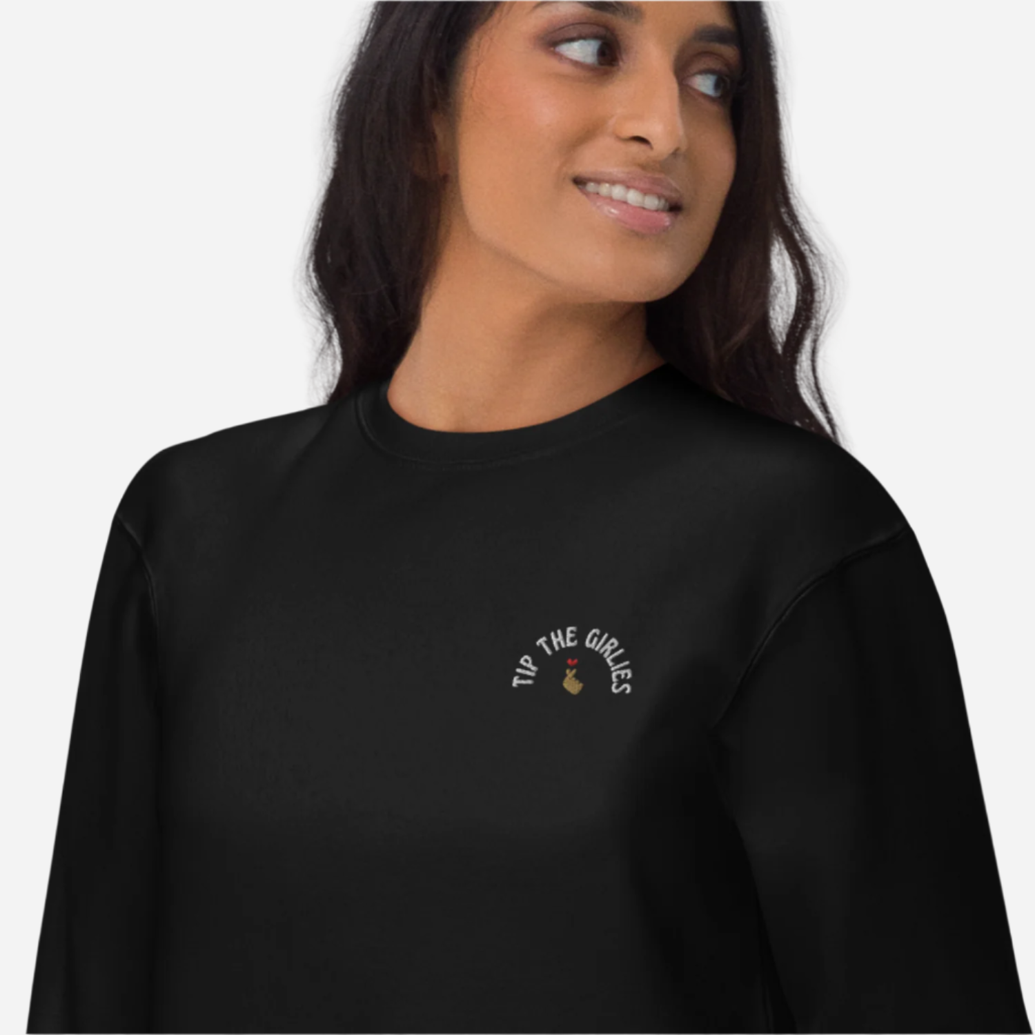 Woman in front of a white background wearing a black sweater with the words 