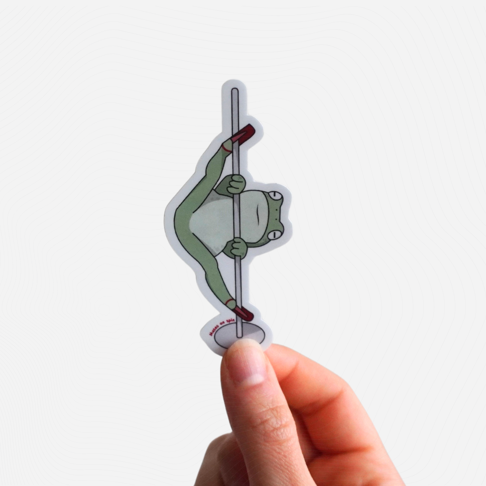 Hand holding a sticker of a cartoon frog on a pole against a white background