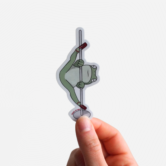 Hand holding a sticker of a cartoon frog on a pole against a white background