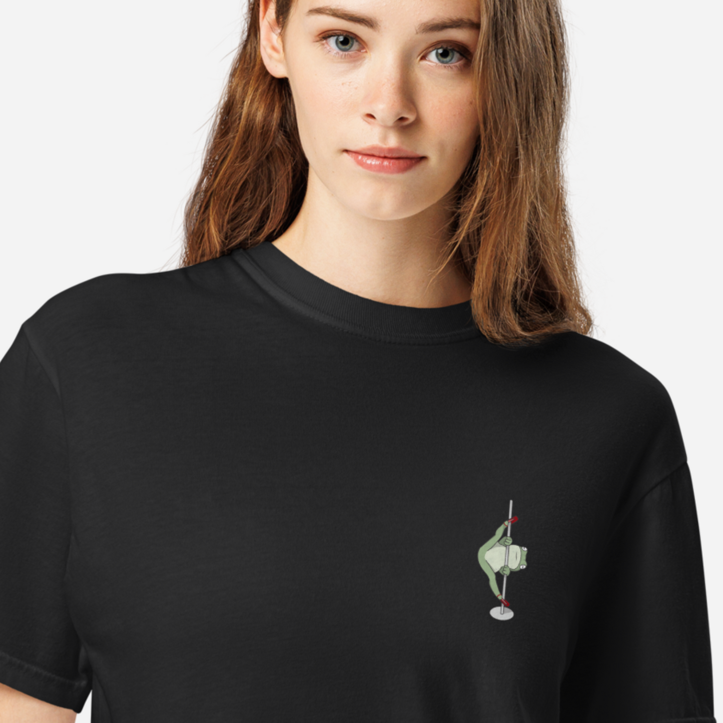 Woman wearing a black tshirt with a small graphic of a frog in high heels doing the splits on a pole. 