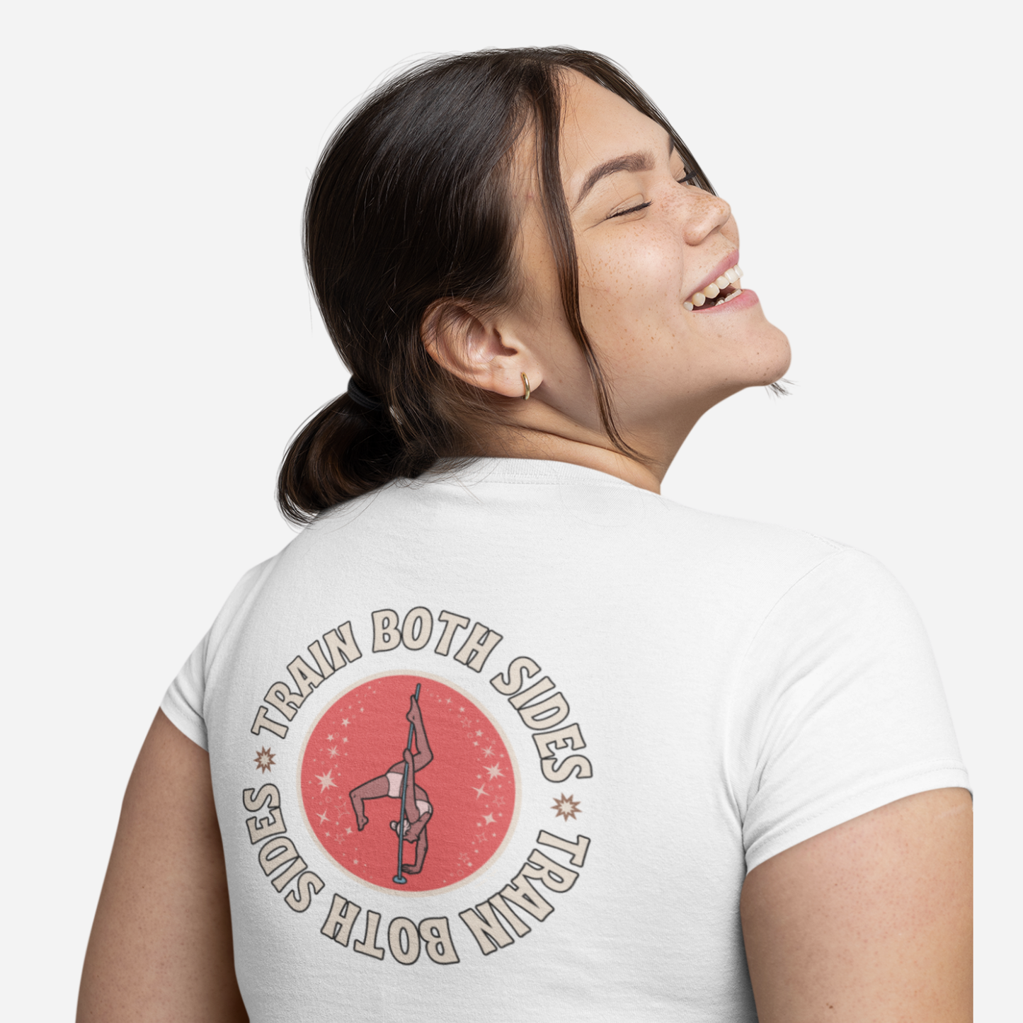 Woman facing away and looking to the side, standing in front of a white background. She is wearing a white tshirt with a graphic stating "Train Both Sides".