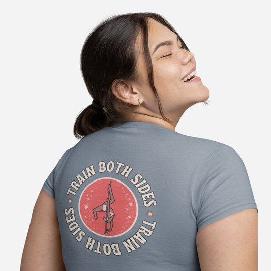 Woman facing away and looking to the side, standing in front of a white background. She is wearing a light blue tshirt with a graphic stating "Train Both Sides".