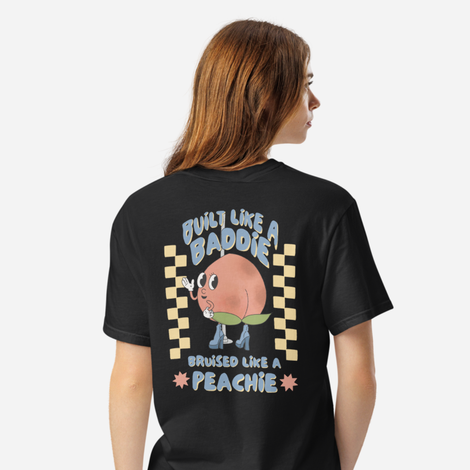 Woman facing the back wearing a black tshirt with a graphic of a cartoon peach. It says 