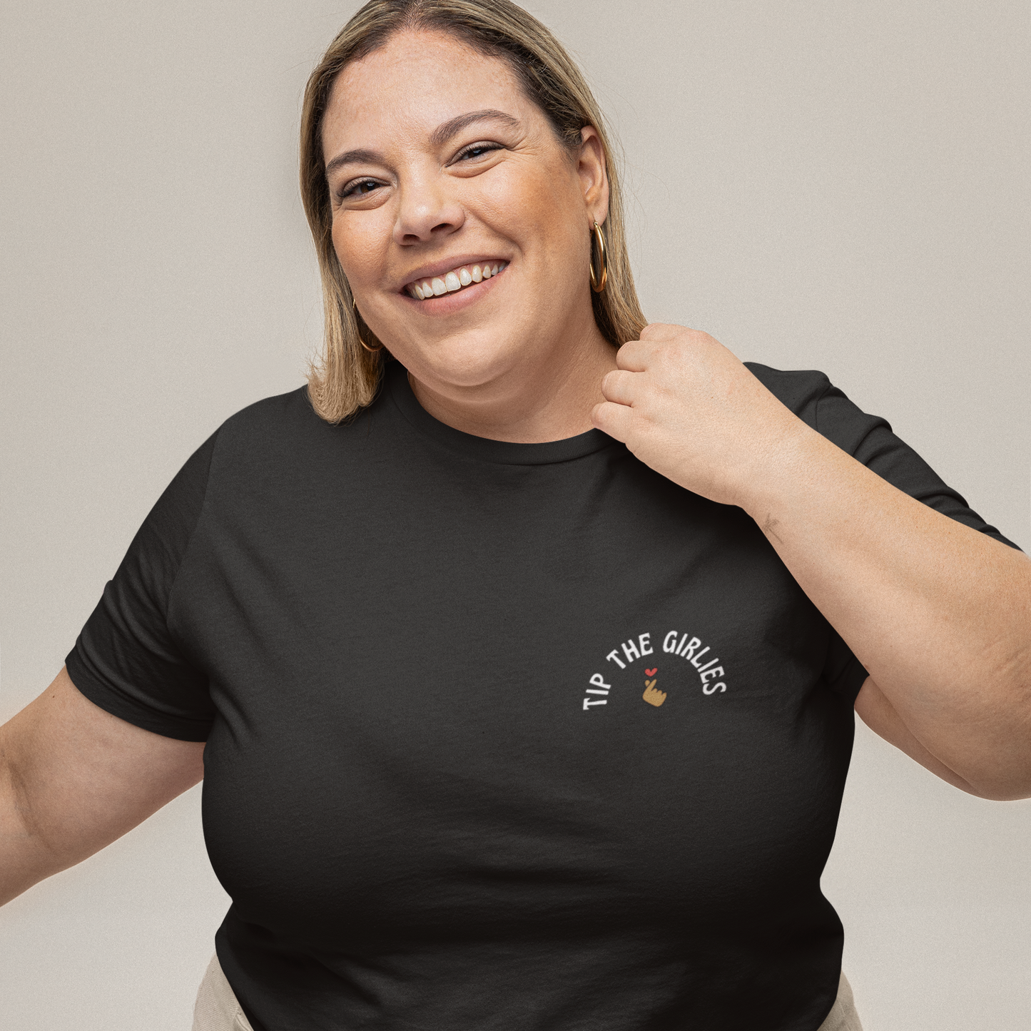 Woman wearing a black tshirt with the words "Tip the Girlies" embroidered on the left chest area.