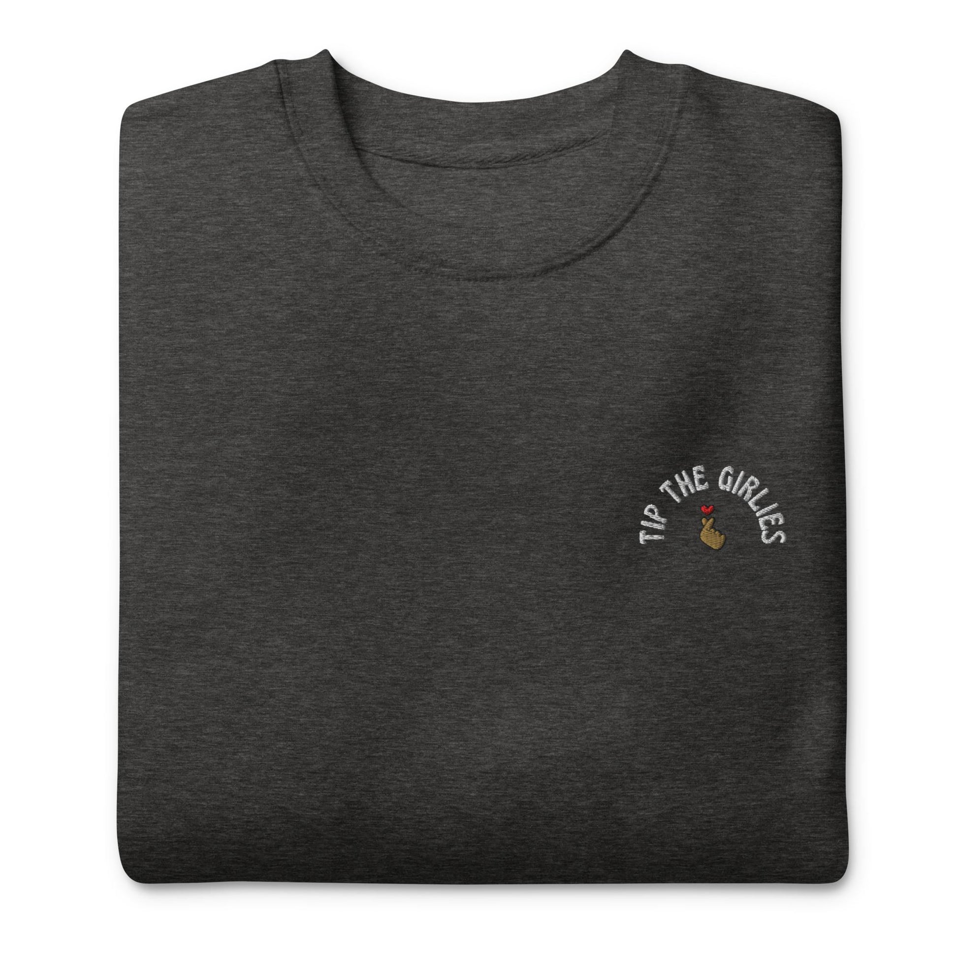 Folded dark grey sweater with the words "Tip the Girlies" embroidered on the left chest area, placed in front of a white background